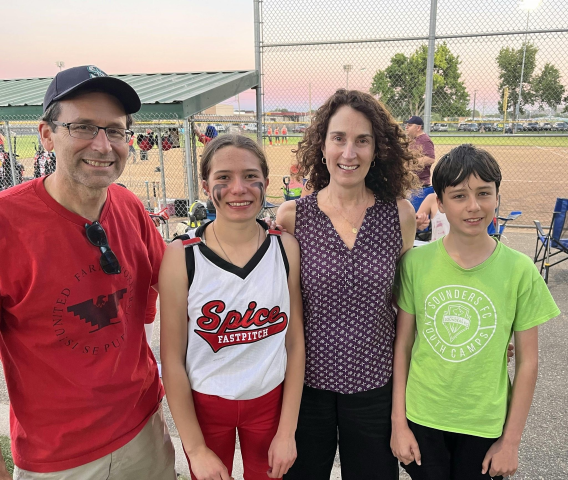 Bob wearing a red tshirt, left, with daughter, wife, and son at a softball field