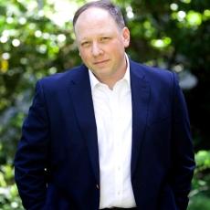 Headshot of David Frockt wearing a navy jacket over a white button up